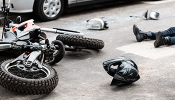 A motorcycle is sprawled on the ground adjacent to a car