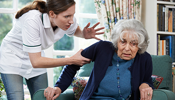 A woman assists an elderly woman seated in a chair